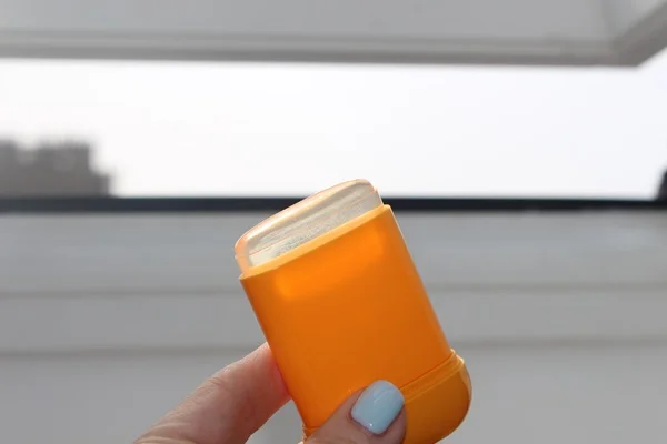 Close-up of the orange Anua sunscreen stick tube and label