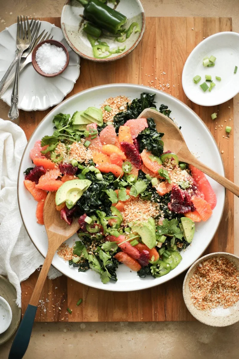 Colorful kale and citrus salad with avocado on a white plate