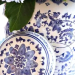 Blue hydrangeas beside ornate porcelain vase in soft morning light