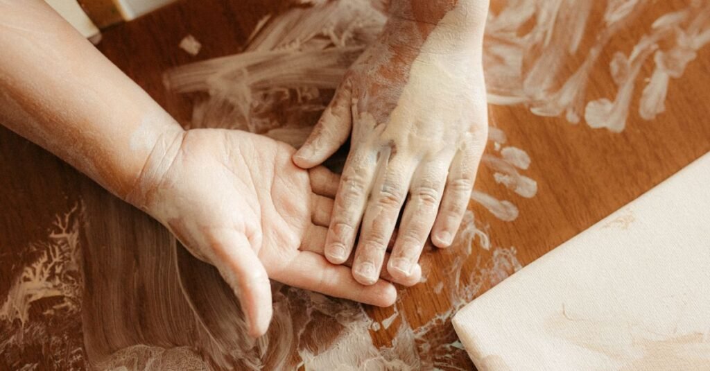 Child's hand and adult hand covered in white paint making a craft
