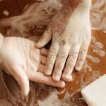 Child's hand and adult hand covered in white paint making a craft