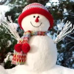 Handmade snowman in fresh snow with red hat and scarf