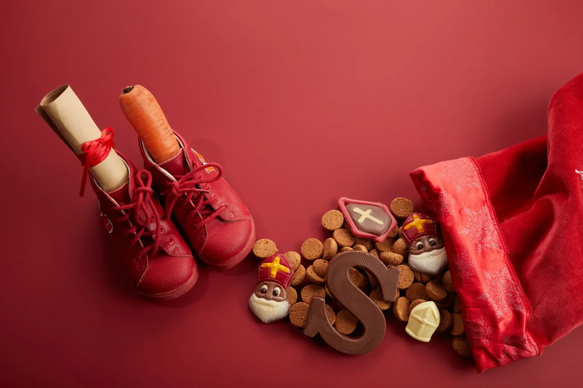 Sinterklaas still life with shoes, cookies, and chocolates on red
