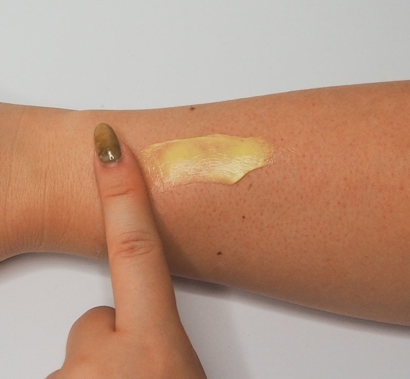 Finger pointing at cream texture swatch on forearm